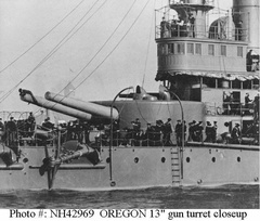 Closeup view of her forward 13-inch gun turret and pilothouse, taken as she was leaving New York for Manila, 12 October 1898. Note man atop one of the guns, and anchors stowed on &quot;billboards&quot;. This image is cropped from NH 61237.